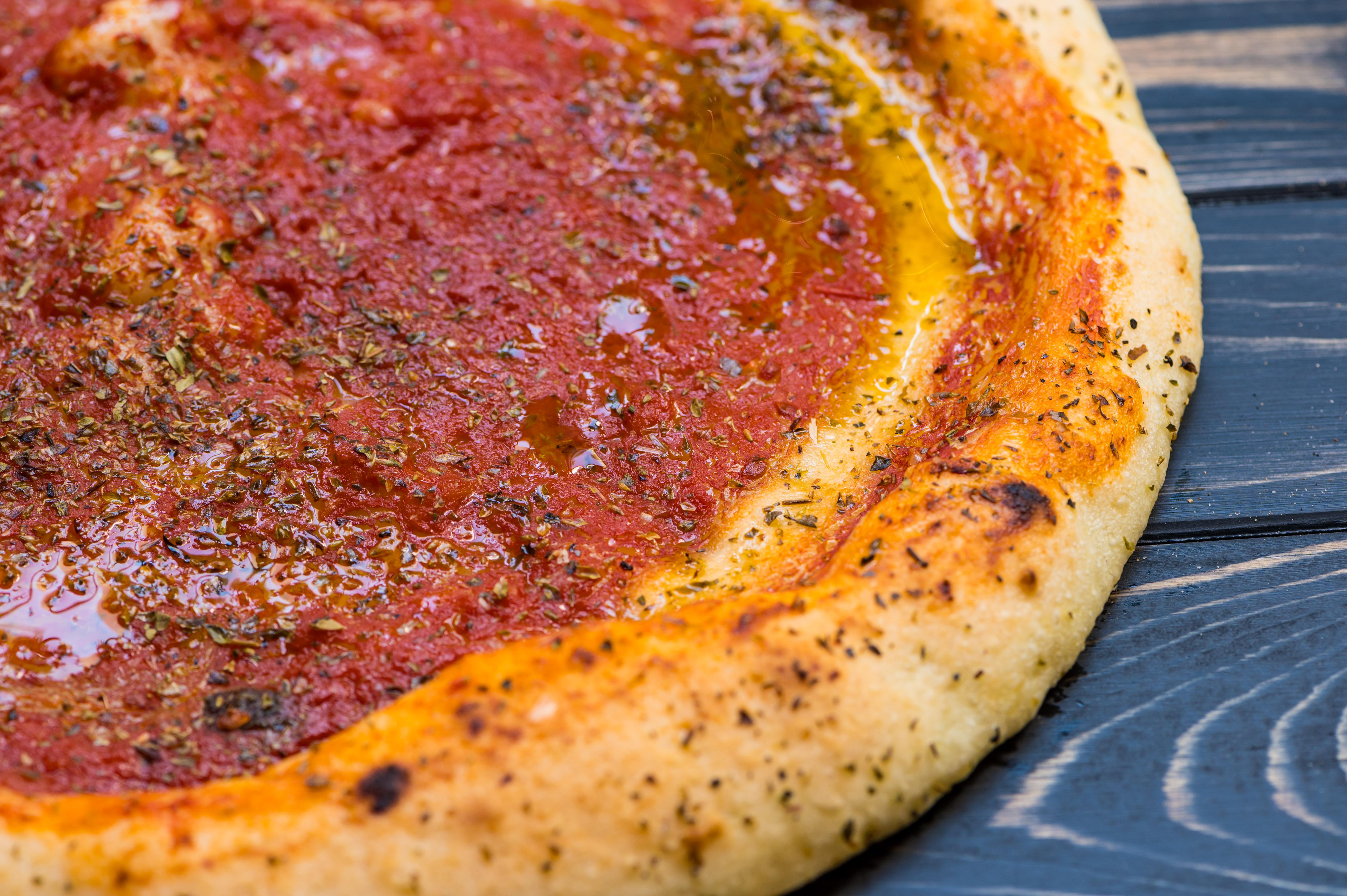 Nahaufnahme einer glutenfreien Pizza Marinara mit Tomatensauce und Oregano